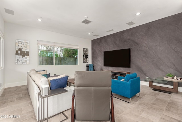 living room with recessed lighting, visible vents, baseboards, and an accent wall