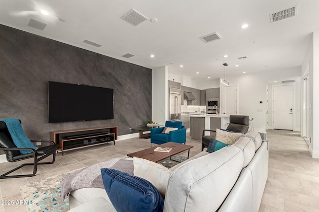 living room with recessed lighting, visible vents, and an accent wall