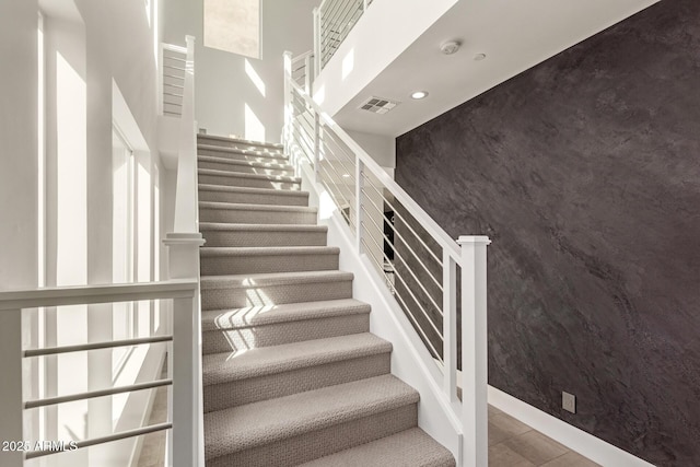 stairs with visible vents, recessed lighting, an accent wall, and baseboards