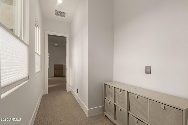 corridor featuring visible vents, light carpet, plenty of natural light, and baseboards