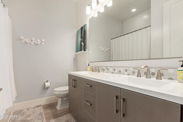 full bath with double vanity, toilet, baseboards, and a sink