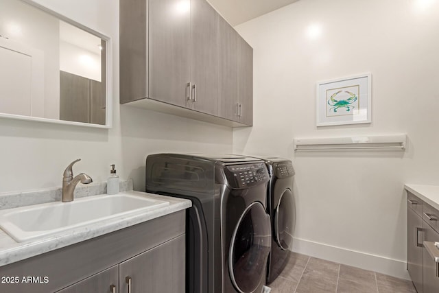 laundry area featuring a sink, baseboards, cabinet space, and washing machine and dryer