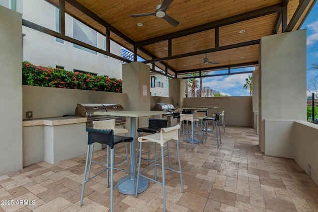 view of patio with outdoor dining space, outdoor wet bar, area for grilling, ceiling fan, and grilling area