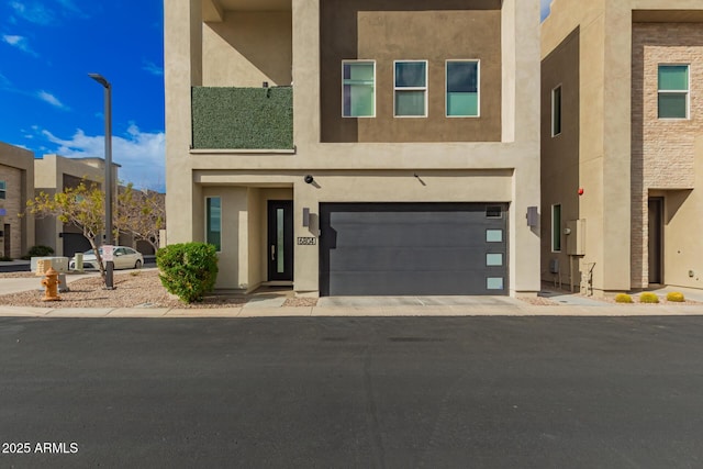 view of front of house with an attached garage, driveway, and stucco siding