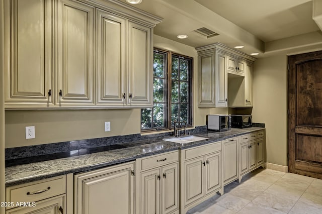 10894 E Turquoise Ave, Scottsdale, AZ 85259 - kitchen featuring dark stone counters, cream cabinets, visible vents, and a sink