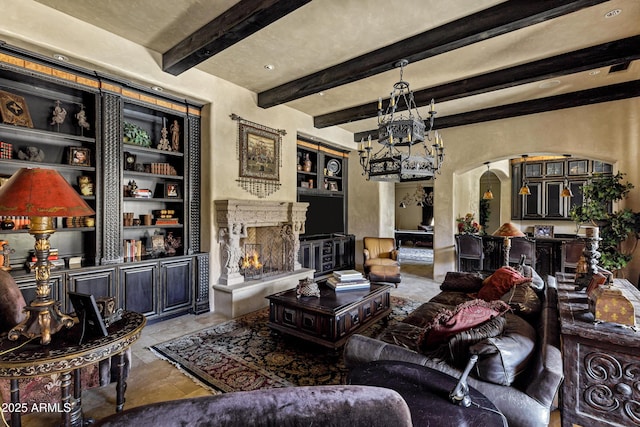 10894 E Turquoise Ave, Scottsdale, AZ 85259 - living room featuring built in shelves, beam ceiling, a fireplace, arched walkways, and a notable chandelier