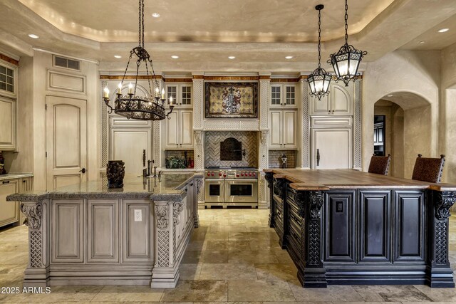 10894 E Turquoise Ave, Scottsdale, AZ 85259 - kitchen with visible vents, premium appliances, a large island with sink, a notable chandelier, and a raised ceiling
