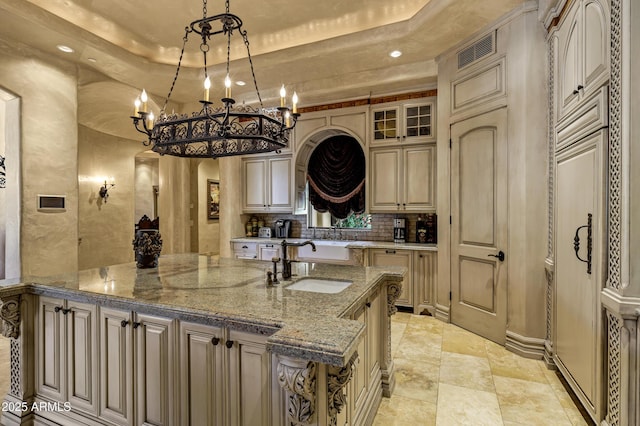 10894 E Turquoise Ave, Scottsdale, AZ 85259 - kitchen with light stone countertops, visible vents, a sink, a raised ceiling, and tasteful backsplash