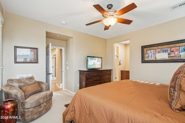 bedroom with ceiling fan, light carpet, and connected bathroom