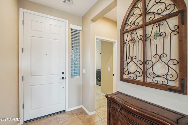 tiled foyer entrance with washer / dryer