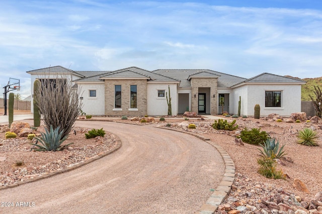 view of front of home with curved driveway, a tiled roof, and stucco siding