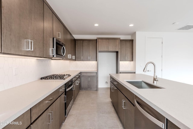 kitchen featuring decorative backsplash, sink, appliances with stainless steel finishes, light tile patterned floors, and dark brown cabinets