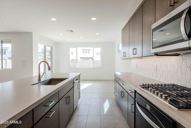 kitchen featuring backsplash, dark brown cabinets, sink, and stainless steel appliances