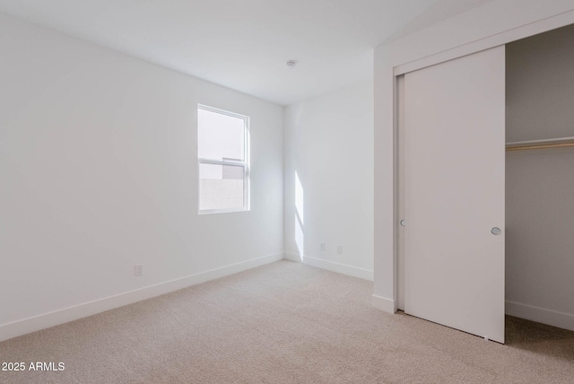 unfurnished bedroom featuring light carpet and a closet