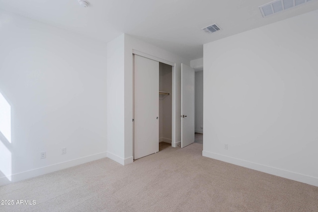 unfurnished bedroom with light carpet and a closet