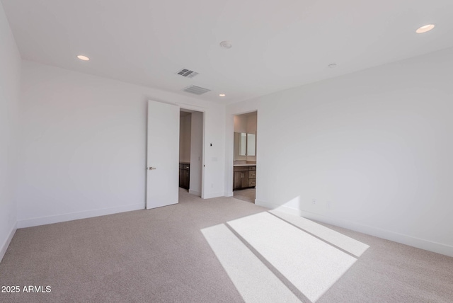 unfurnished bedroom featuring light carpet and ensuite bath