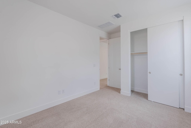 unfurnished bedroom featuring a closet and light carpet