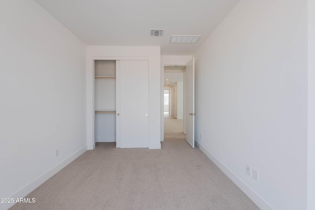 unfurnished bedroom with a closet and light colored carpet