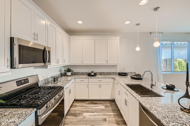 kitchen with pendant lighting, white cabinets, sink, kitchen peninsula, and stainless steel appliances