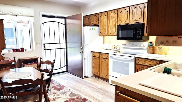 2064 S Farnsworth Dr Unit 38, Mesa, AZ 85209 - kitchen featuring white appliances, light countertops, light wood-type flooring, brown cabinetry, and a sink