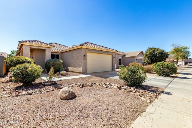 view of front facade featuring a garage, concrete driveway, a tile roof, and stucco siding