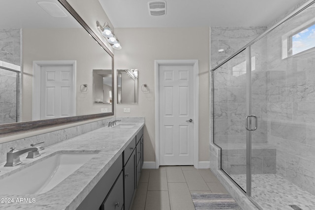 bathroom featuring a stall shower, double vanity, a sink, and tile patterned floors