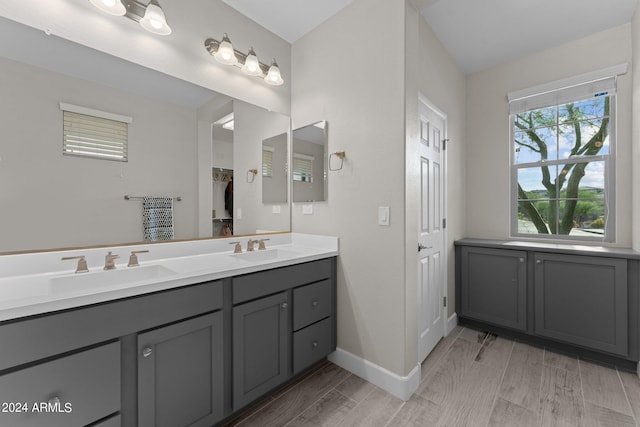 bathroom featuring wood finish floors, a sink, baseboards, and double vanity