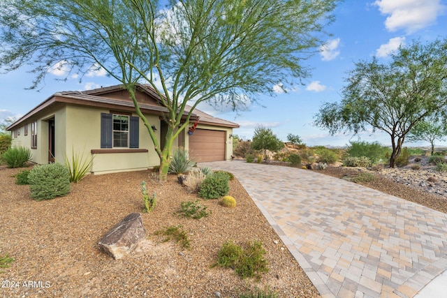 single story home with a garage, decorative driveway, and stucco siding