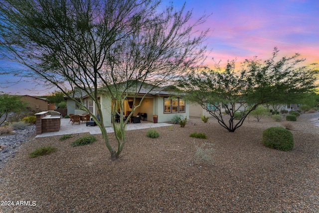 back of house at dusk with a patio and stucco siding