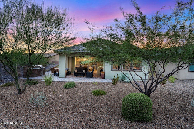 back of property at dusk with stucco siding, an outdoor hangout area, and a patio