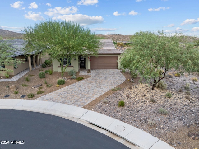 view of front facade featuring a garage, decorative driveway, a mountain view, and stucco siding