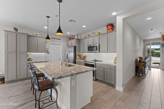 kitchen featuring light stone counters, pendant lighting, visible vents, appliances with stainless steel finishes, and a kitchen breakfast bar