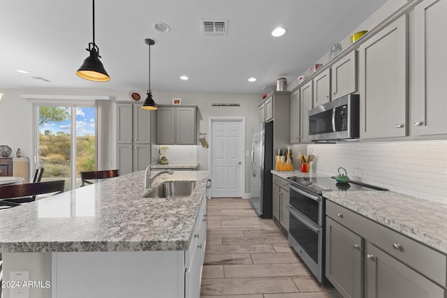 kitchen featuring decorative light fixtures, stainless steel appliances, gray cabinets, visible vents, and a sink