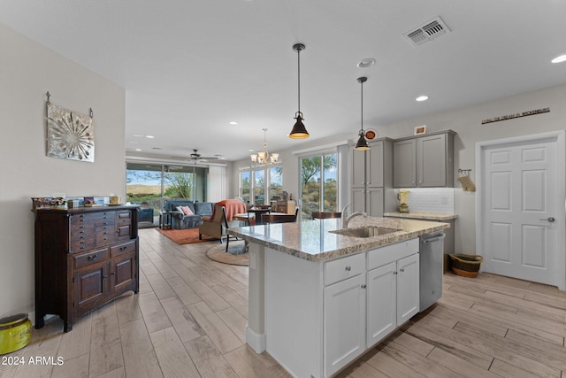 kitchen with light stone counters, a sink, visible vents, open floor plan, and light wood-type flooring