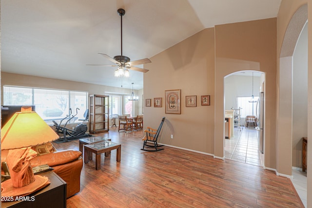 living room with hardwood / wood-style flooring, vaulted ceiling, and ceiling fan with notable chandelier