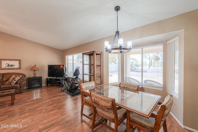 dining room with a chandelier, vaulted ceiling, and hardwood / wood-style floors