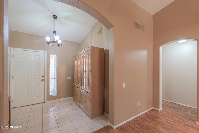 entrance foyer with lofted ceiling, light hardwood / wood-style flooring, and an inviting chandelier