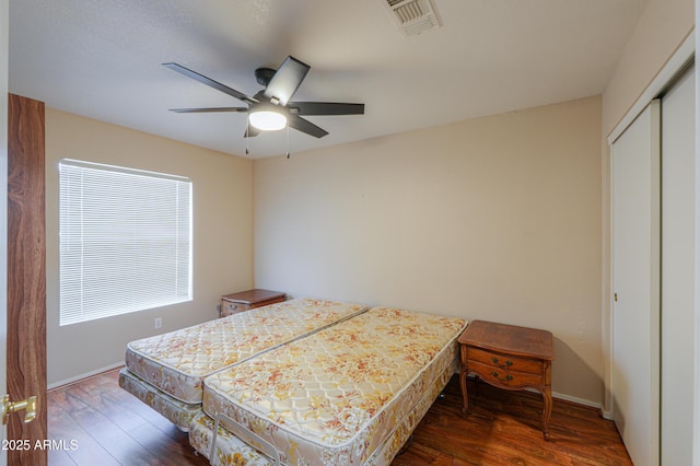 bedroom featuring dark wood-type flooring, a closet, and ceiling fan