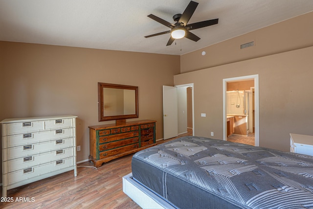 bedroom featuring hardwood / wood-style floors, ensuite bath, vaulted ceiling, and ceiling fan