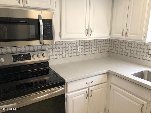 kitchen featuring white cabinets, tasteful backsplash, stainless steel appliances, and tile patterned flooring