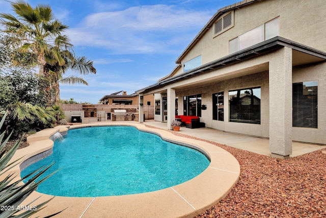 view of pool with pool water feature, exterior kitchen, and a patio