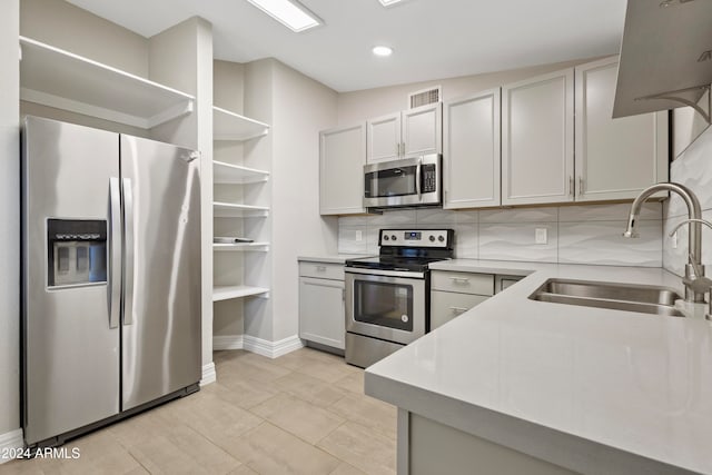 kitchen featuring stainless steel appliances, white cabinetry, sink, tasteful backsplash, and light tile patterned floors