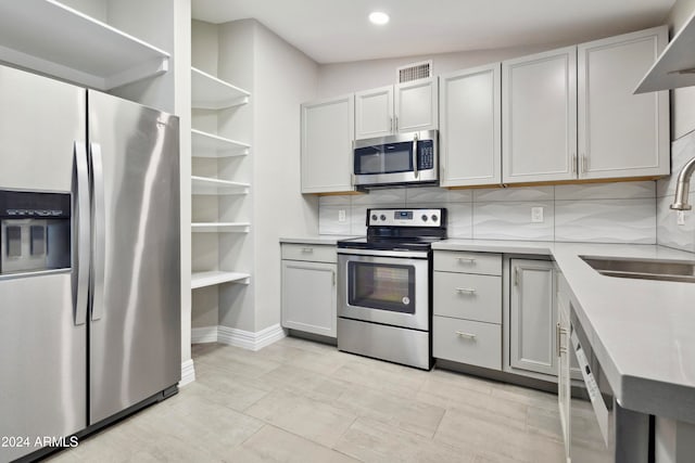 kitchen with vaulted ceiling, decorative backsplash, sink, light tile patterned flooring, and appliances with stainless steel finishes