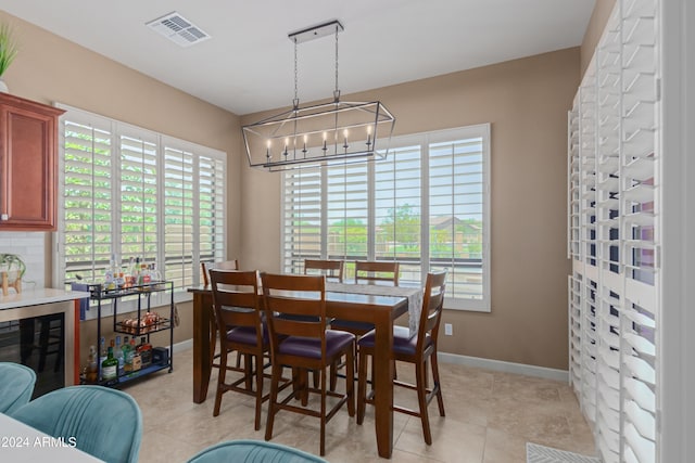 dining room with beverage cooler, a notable chandelier, and light tile patterned flooring