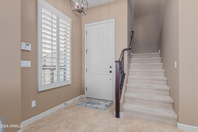 tiled entrance foyer with a healthy amount of sunlight and a chandelier