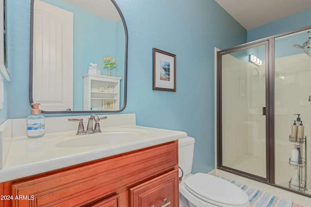 bathroom featuring vanity, toilet, and a shower with shower door