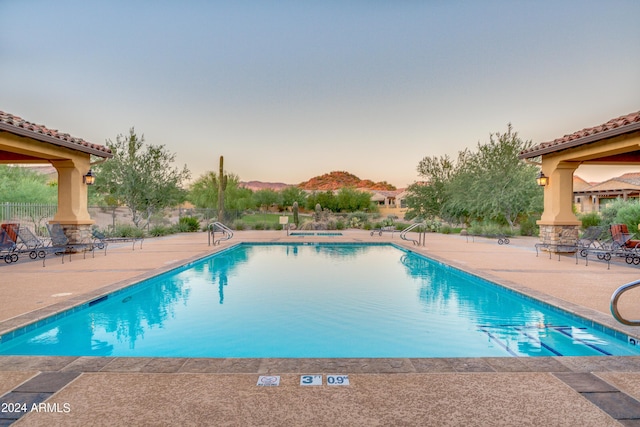 pool at dusk featuring a patio area