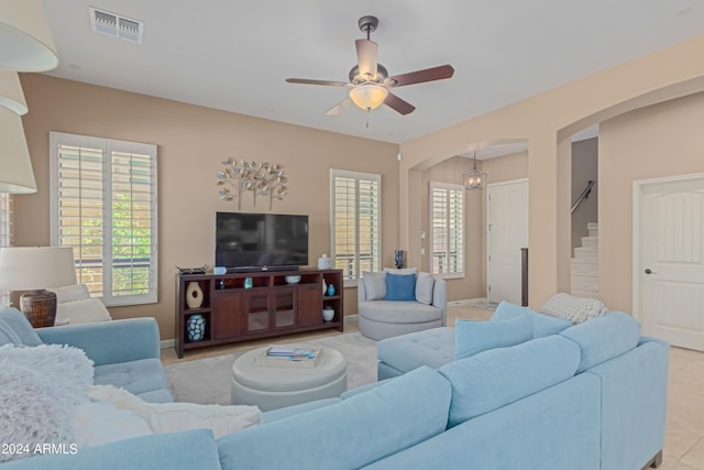 living room with light tile patterned floors and ceiling fan with notable chandelier