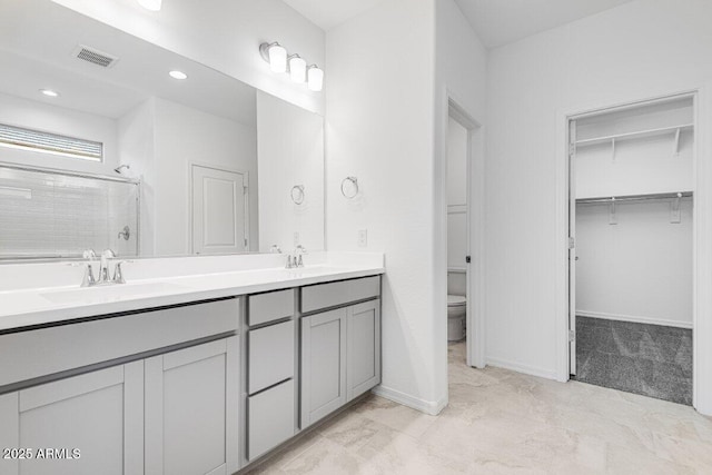 bathroom with double vanity, a shower stall, visible vents, and a sink