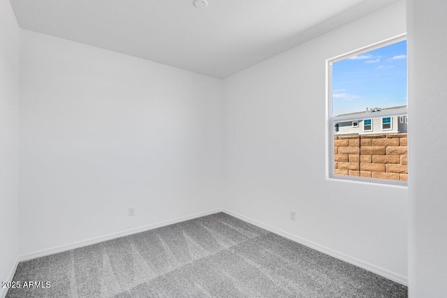 carpeted empty room featuring baseboards